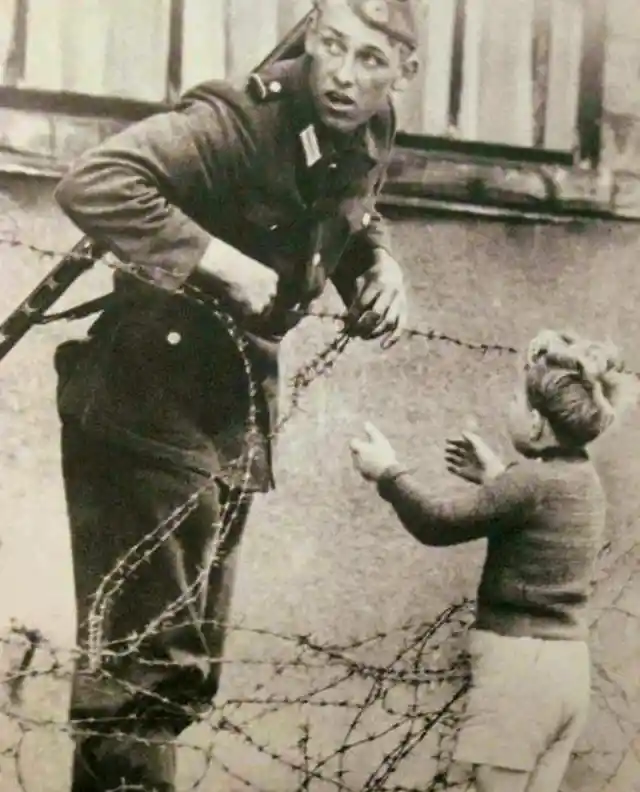 A German soldier disobeying direct orders to help a small boy across the Berlin Wall